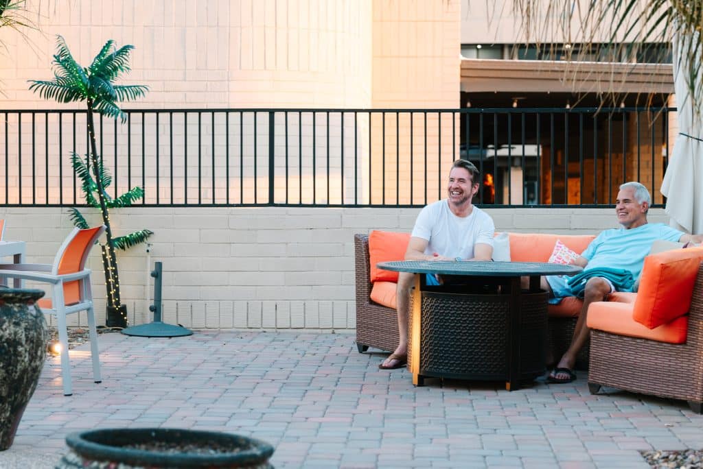 Two happy men are sitting on the couch in Mesa, AZ