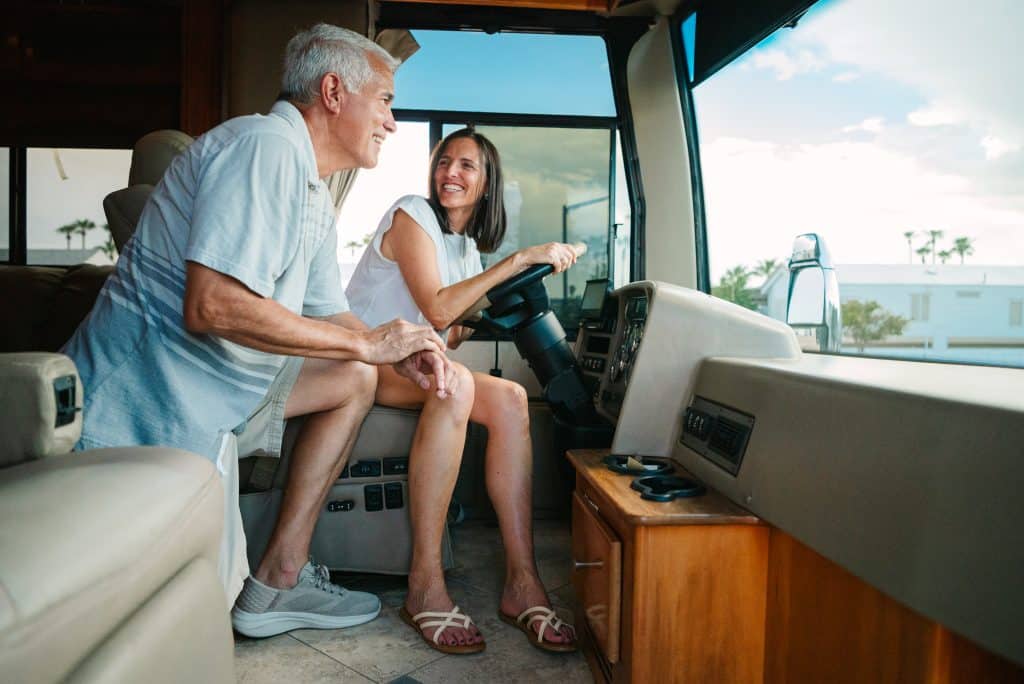 A happy couple is on the RV and the woman holding the steering wheel